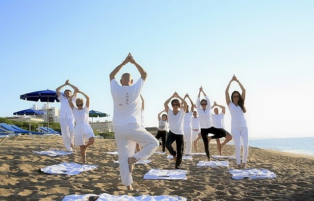 skupina lidí cvičí jógu na pláži u moře